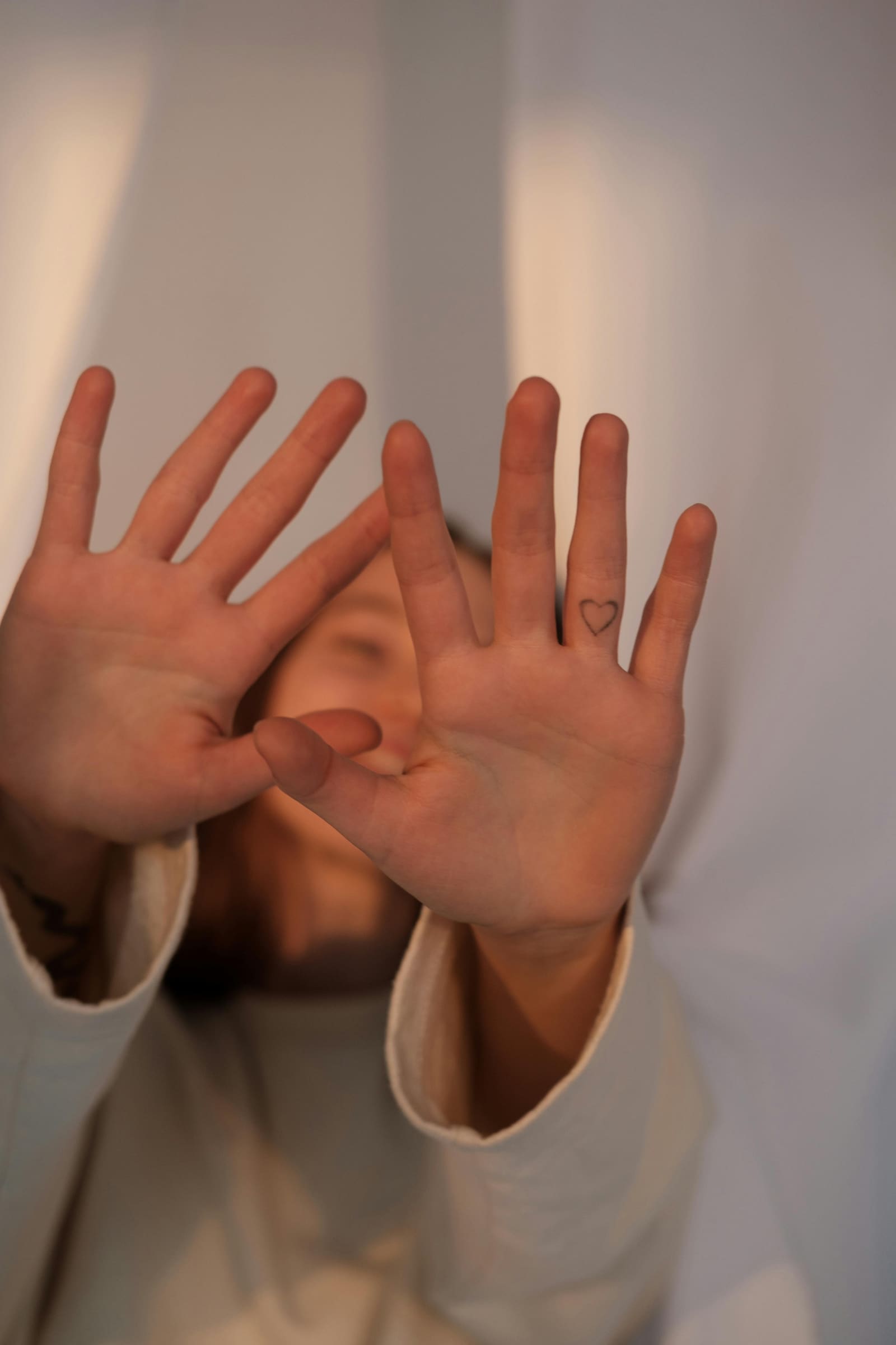 Close-up of hands reaching out, with a small heart tattoo